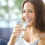 Donna sorridente che beve bicchiere d'acqua